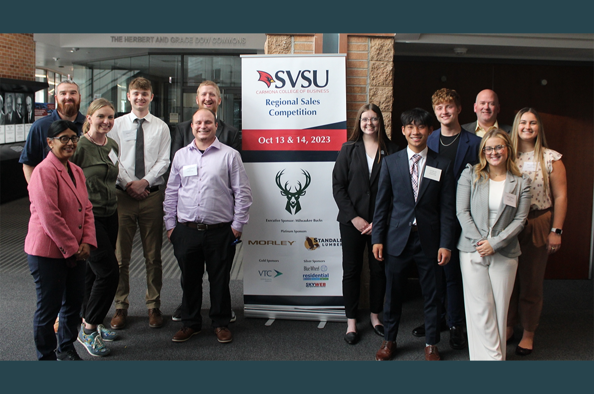 group of people flank a stand-up banner